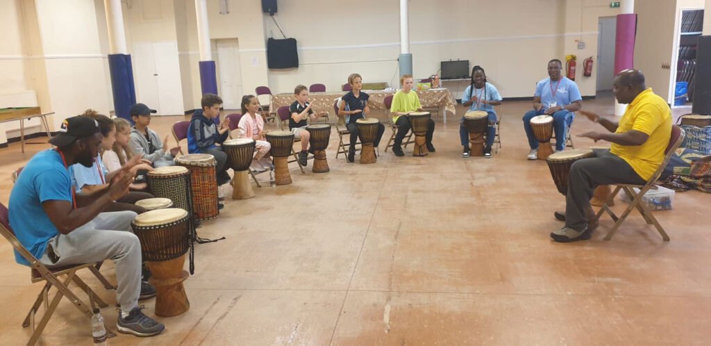 Children and activity leaders taking part in a group drumming session