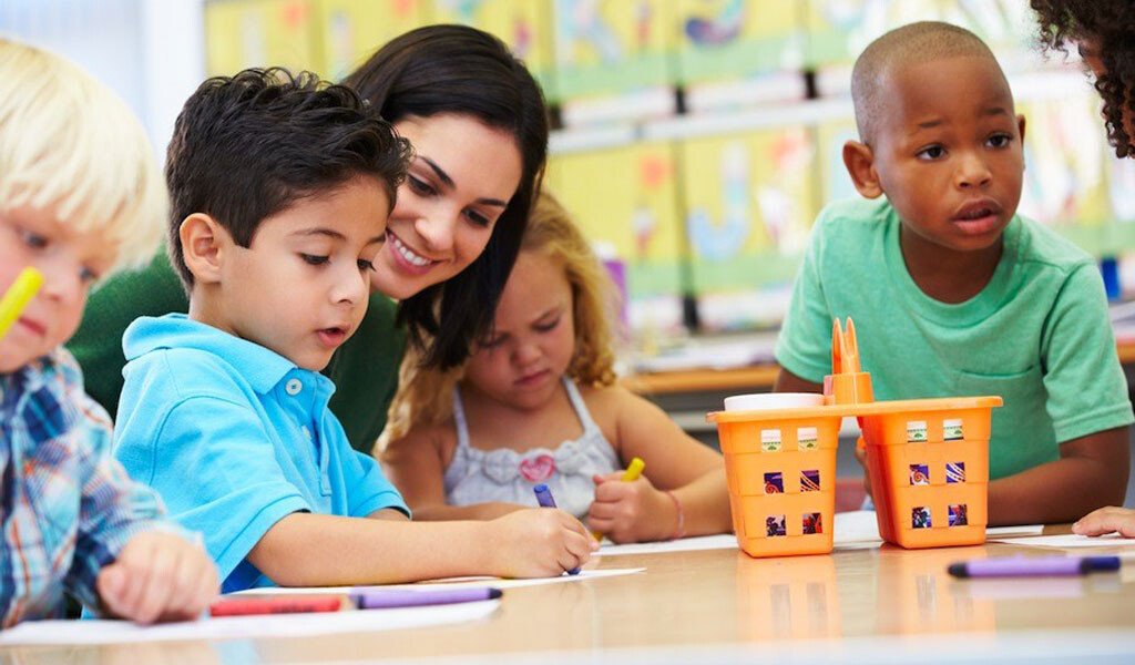 An early years practitioner helping children with a table activity