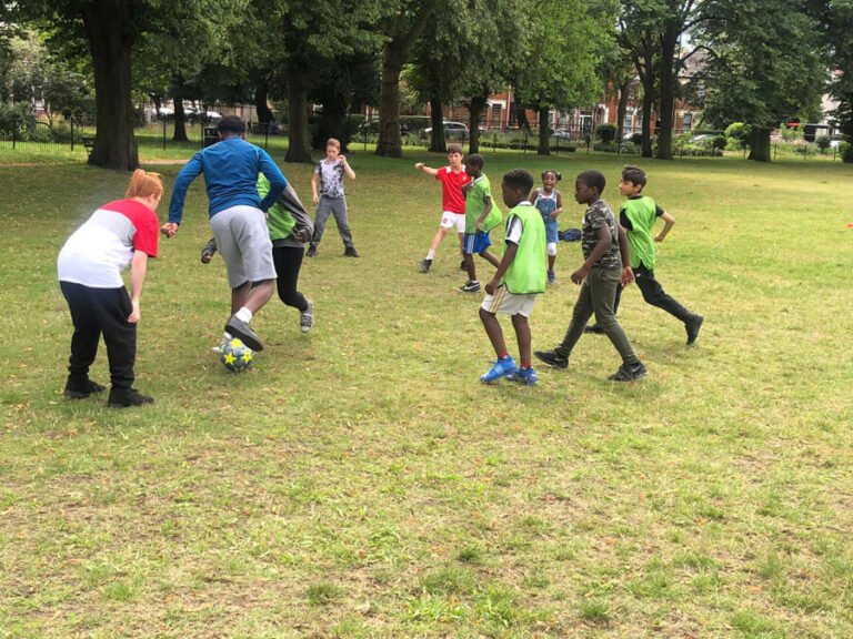 Children and activity leaders playing a group game on the grass