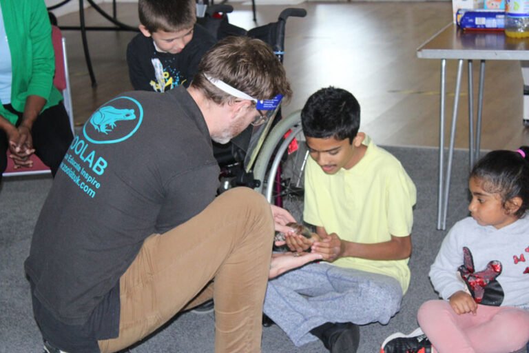 An activity leader supporting children during an animal encounter