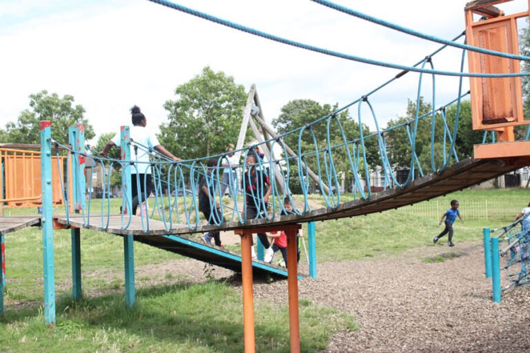 A group of children moving across an outdoor rope course