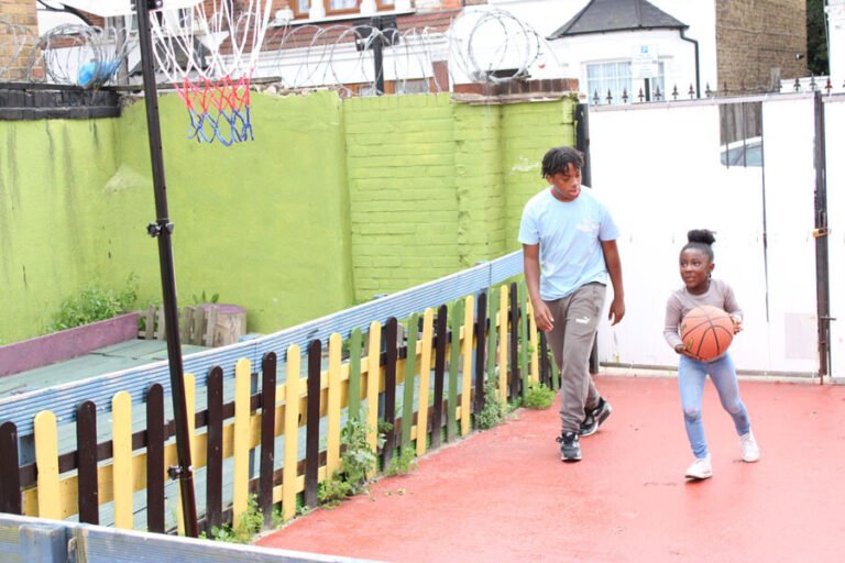 Two children playing basketball in an outdoor activity area