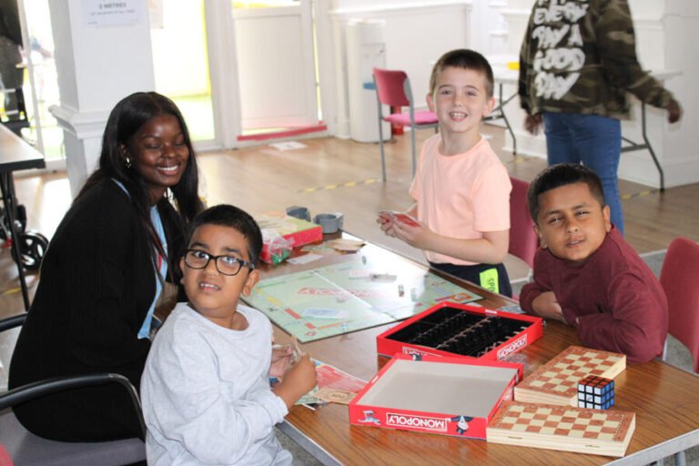 Children smiling together around a board game