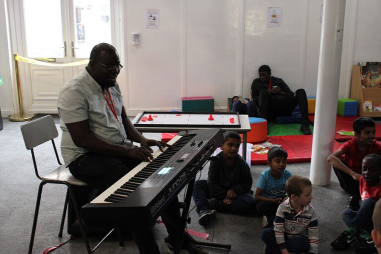 A musician playing keyboard for children during an indoor session