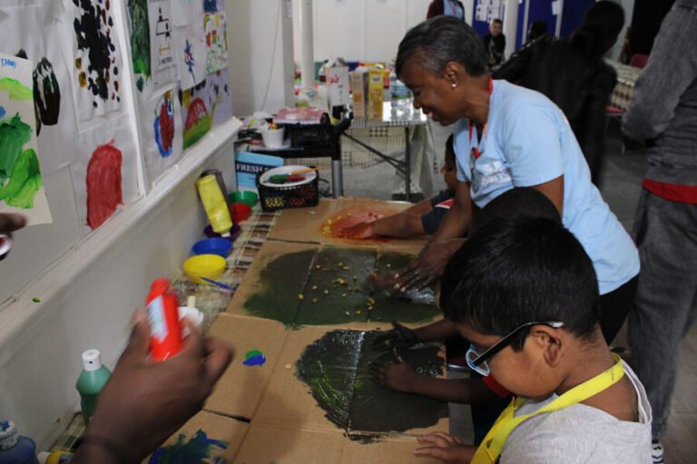 A child working on a colourful art activity with adult support