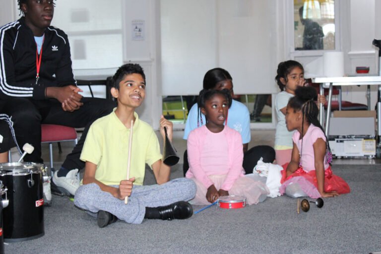 Children seated together with drums and percussion instruments