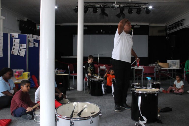 A facilitator leading a percussion workshop for children