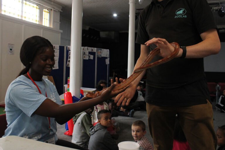A child supported by an activity leader during an animal encounter