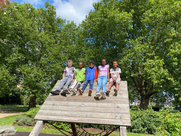 Children sitting together on an outdoor climbing structure