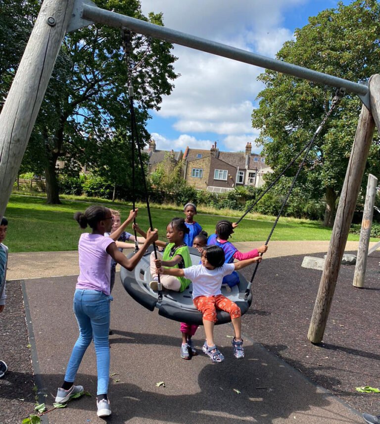 Children and an activity leader enjoying a playground swing