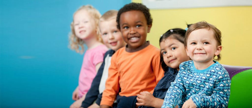 Four young children sitting together in a bright childcare setting